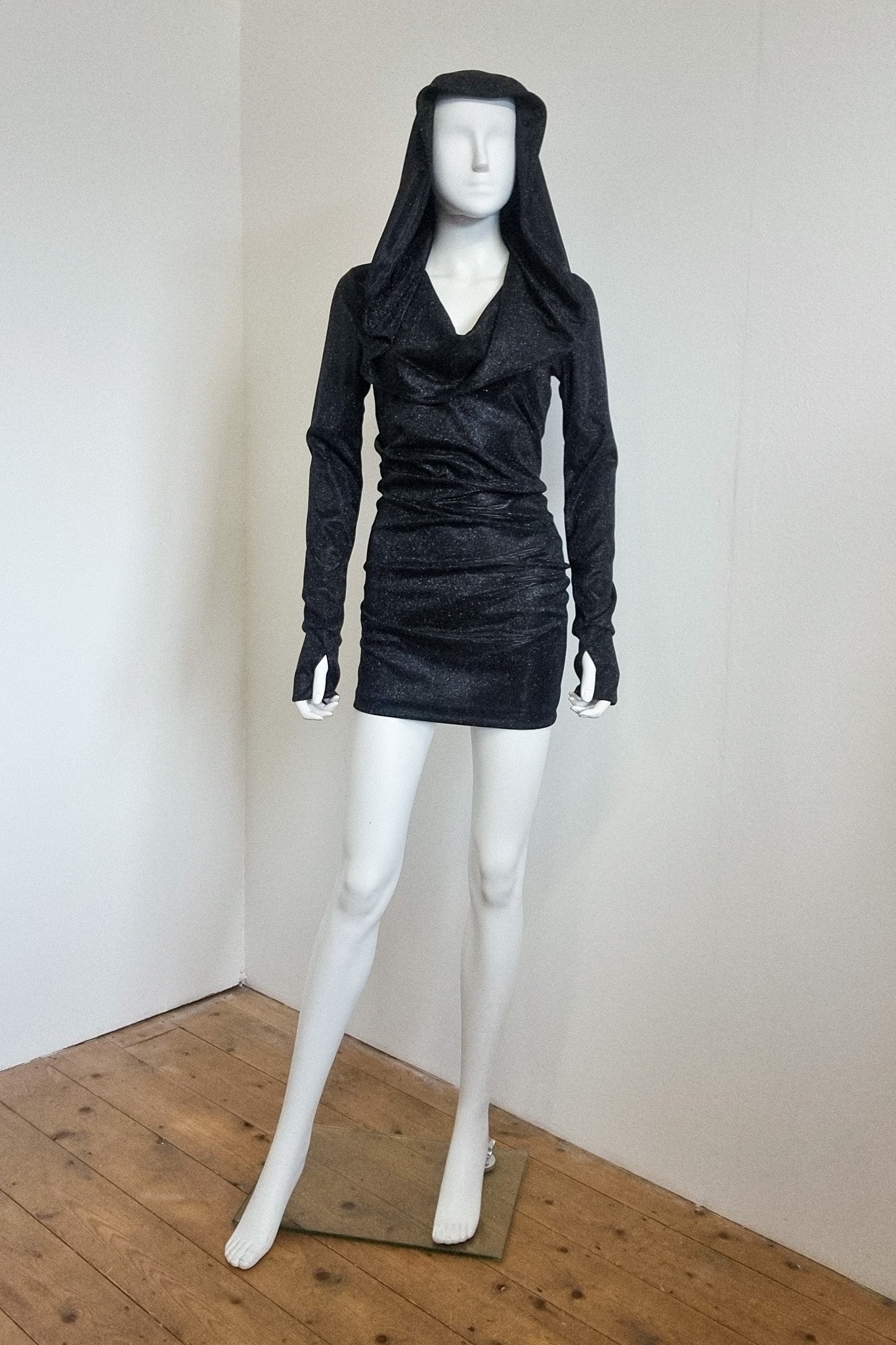 Mannequin wears the black glitter Grace mini with the hood up, front view