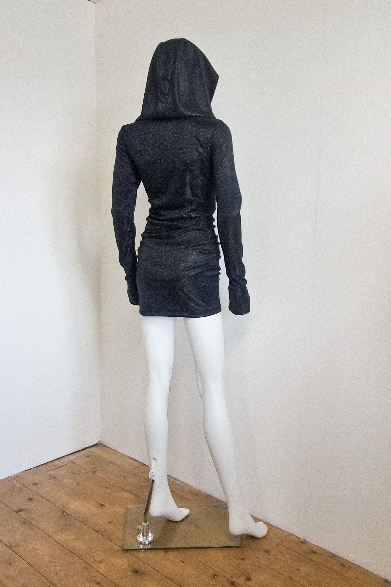 Mannequin wears the black glitter Grace mini with the hood up, back view