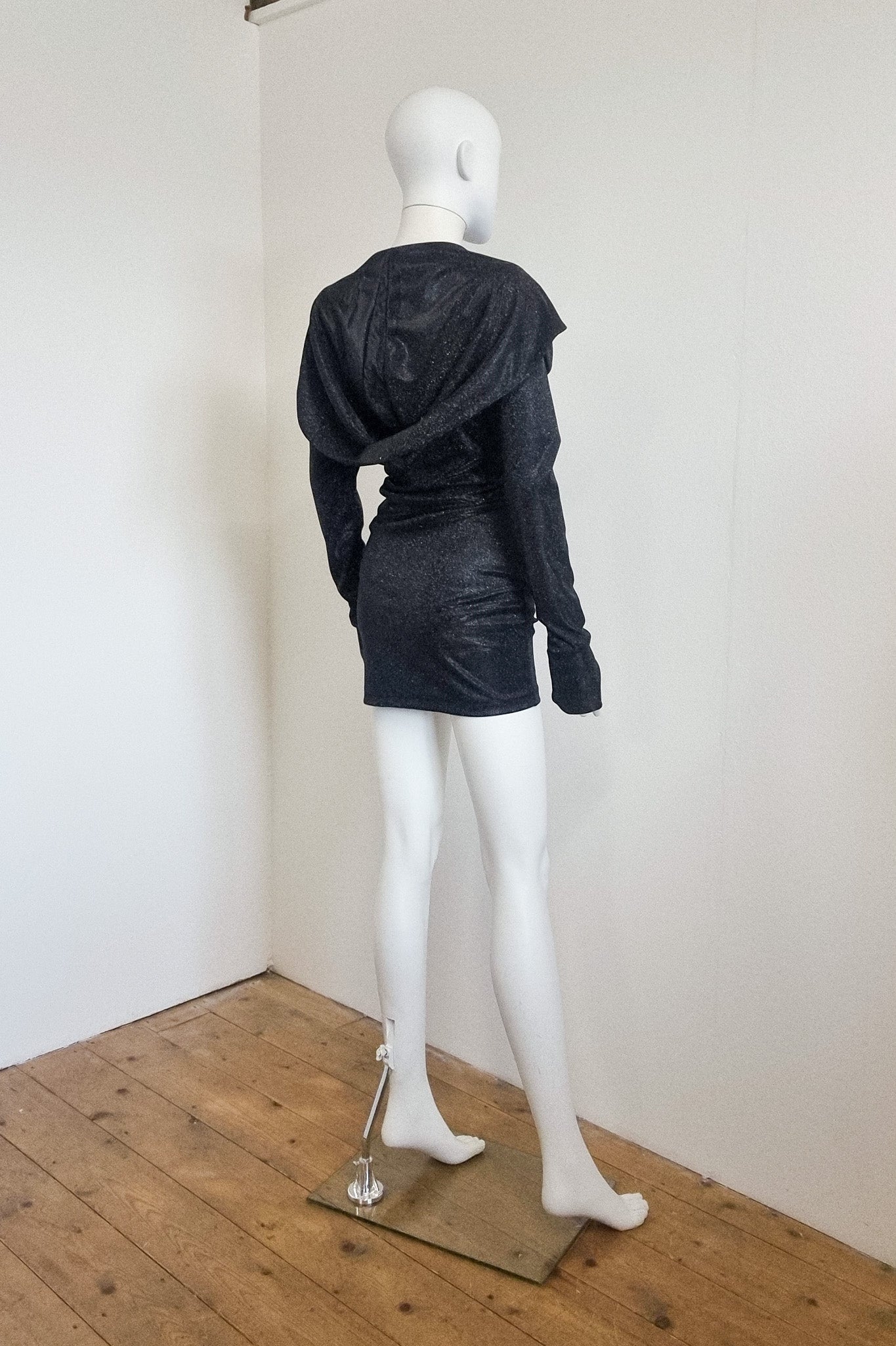 Mannequin wears the black glitter Grace mini with the hood down, back view