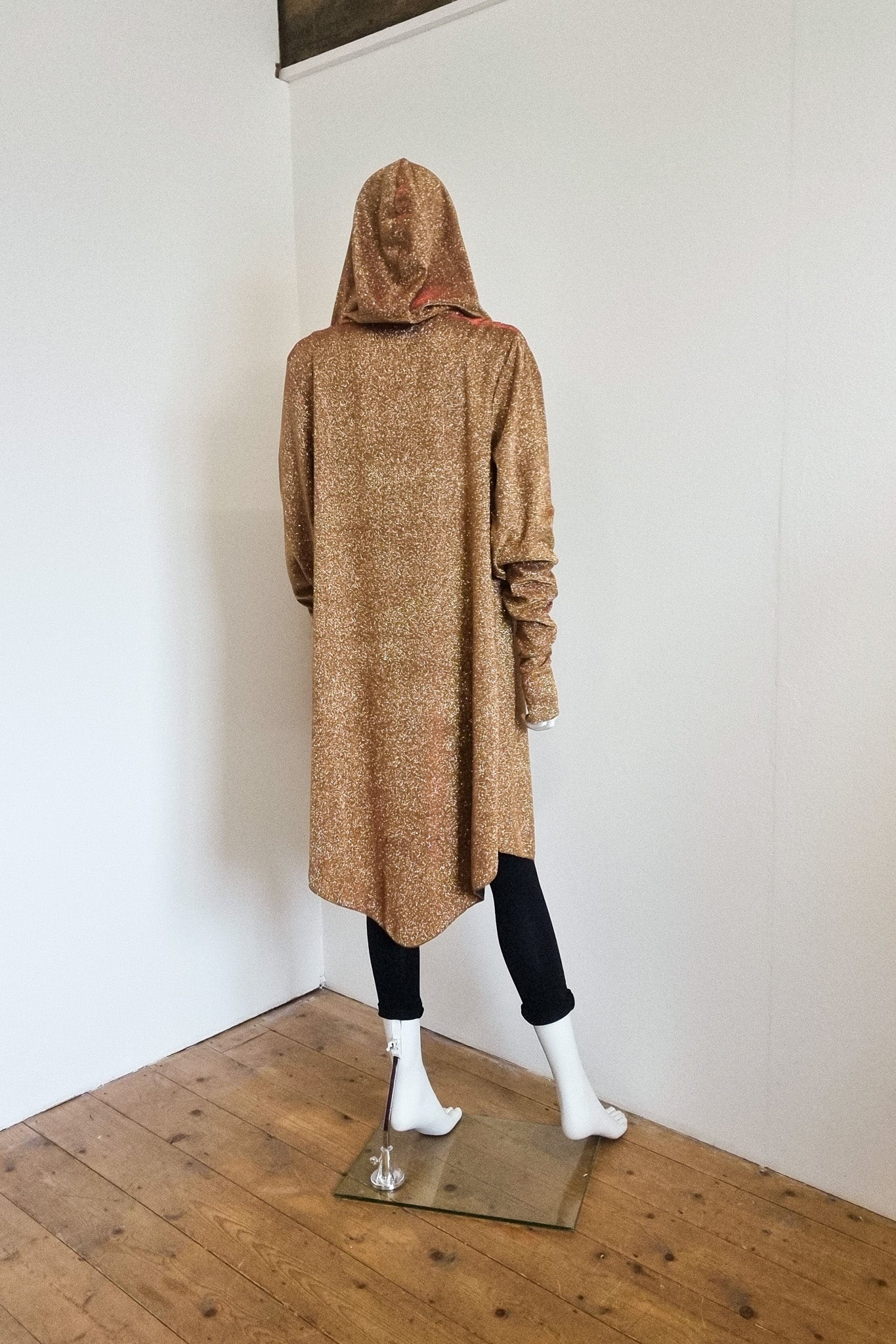 Mannequin wears gold red glitter Miho, dressed down with the hood up, back view