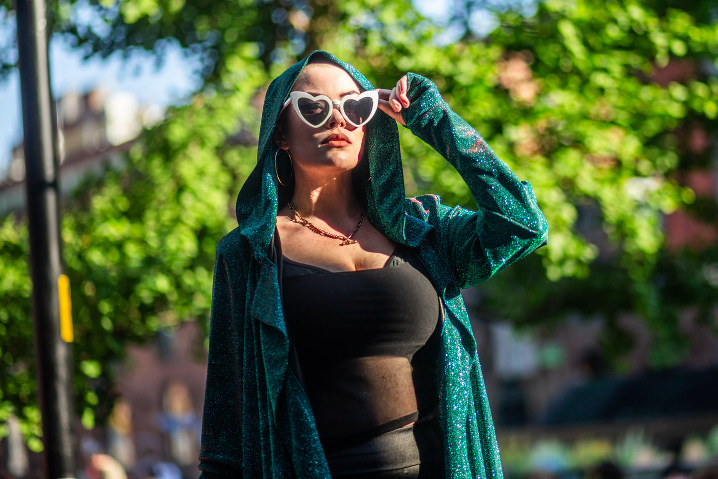 Model Amy wears the Miho cardigan with heart shaped sunglasses. Shadows cut across her face and garment.