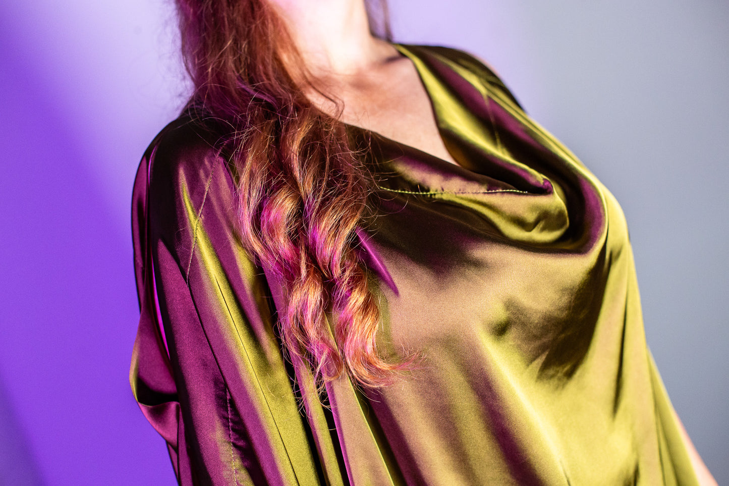 Our model Amy wears the Bea unbelted and shot in a purple light. Detail of the neckline.