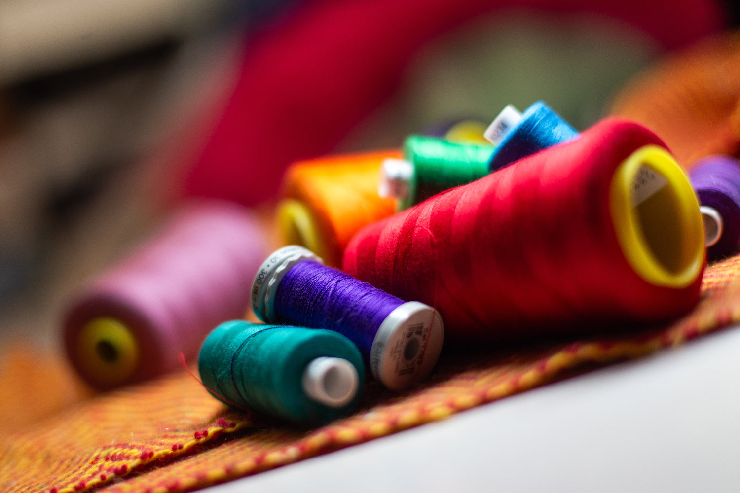 Coloured bobbins of thread on a piece of British wool